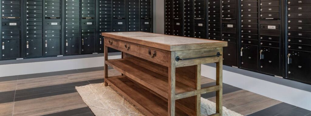 Wooden table in a room with walls lined with black storage lockers, each numbered and equipped with a keyhole.